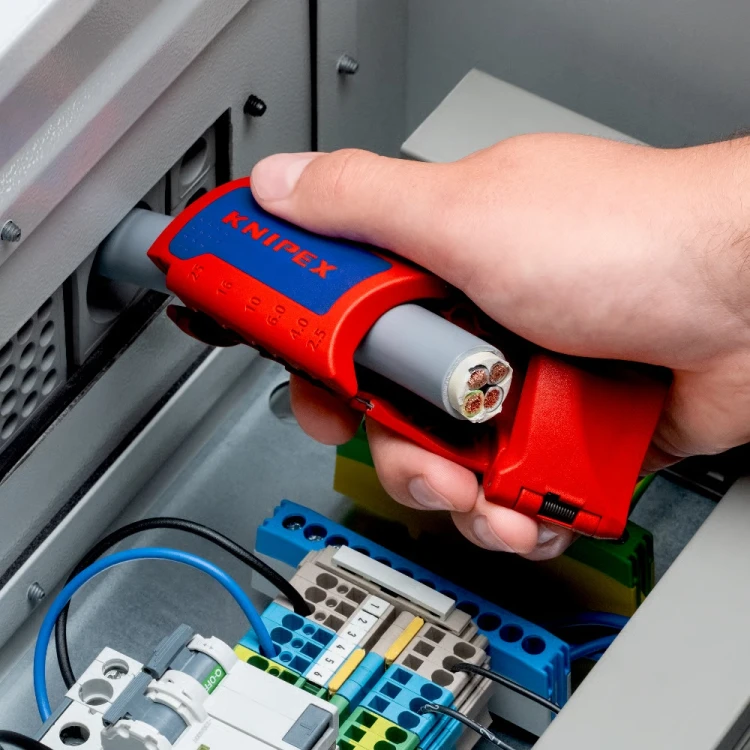 Ściągacz izolacji KNIPEX ErgoStrip XL 16 95 11 – nacinanie zewnętrznego płaszcza grubszego kabla instalacyjnego podczas prac przy rozdzielnicy elektrycznej.